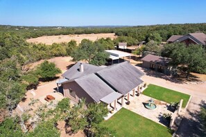 A residential property with a large house, a covered patio, and a well-maintained lawn. - Secluded Hill Country Retreat: Bunkhouse and Spa (Austin)