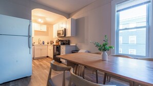 Eine moderne Küche mit weißen Schränken, einem Holztisch und einem Blumentopf.