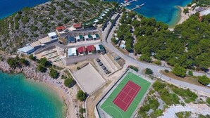 An aerial view of a coastal area with a tennis court, buildings, and a marina. - MH Holiday Dream - Morning Sun (Drage)