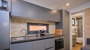 A modern kitchen with a built-in oven, a coffee maker, and a sink. - MH Holiday Dream - Morning Sun (Drage)