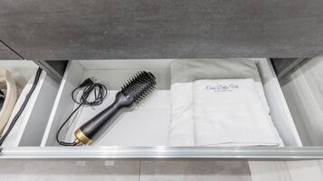 Un tiroir de salle de bain contenant une brosse à cheveux, un sèche-cheveux et une serviette sur laquelle est inscrit « Casa Dolce Vita ».