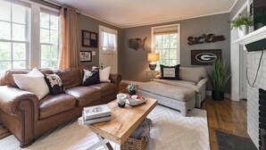 A living room with a brown leather sofa, a grey sofa, a wooden coffee table, and a fireplace. - Five Points Charmer: Delightful 3BR Cottage in Five Points, Complete W/Fire Pit. (Athens)