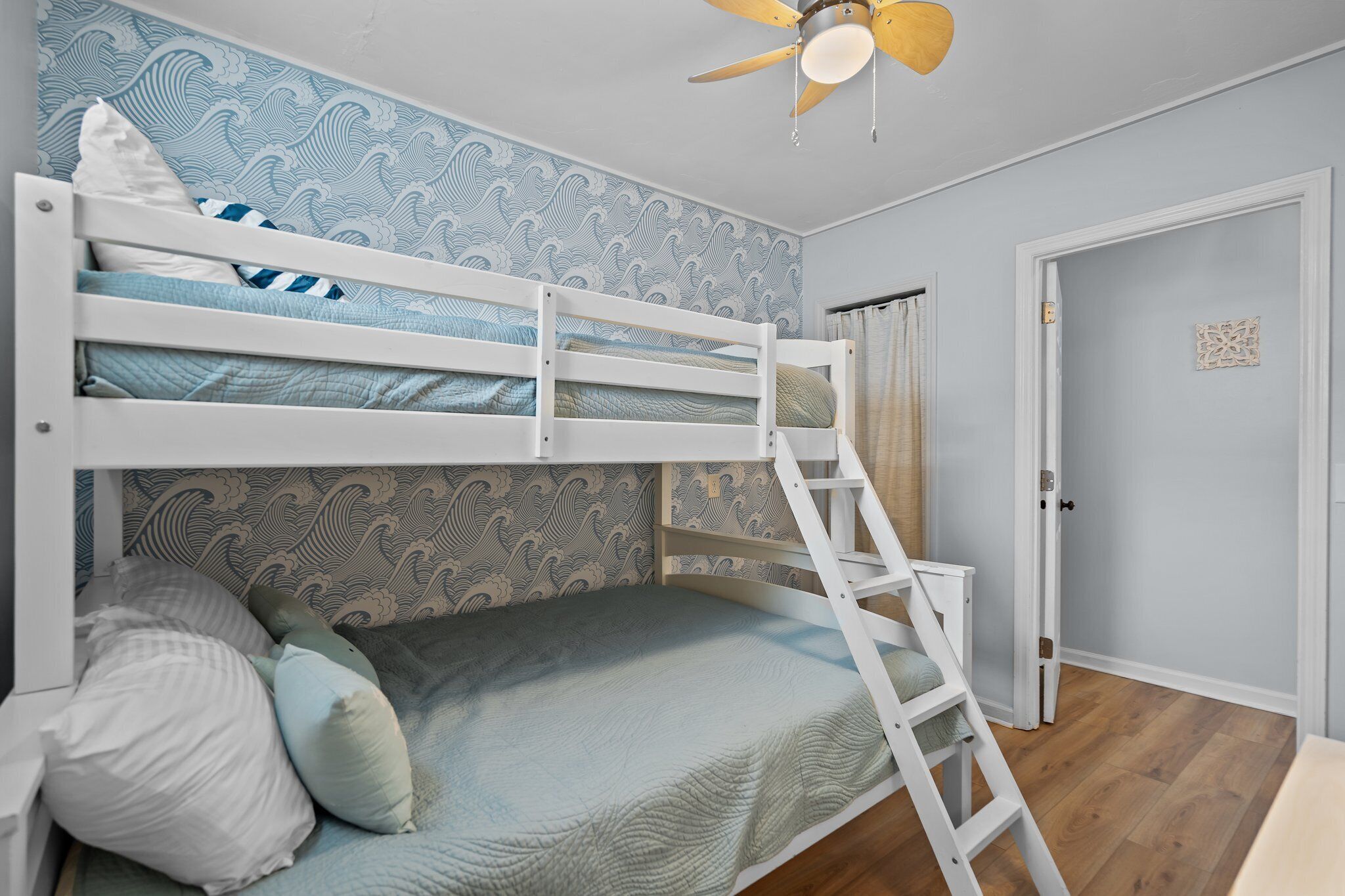 Habitación con literas, escalera, papel tapiz estampado y una puerta.