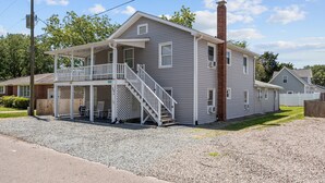 Uma casa de dois andares com varanda coberta e escada que leva ao segundo andar.