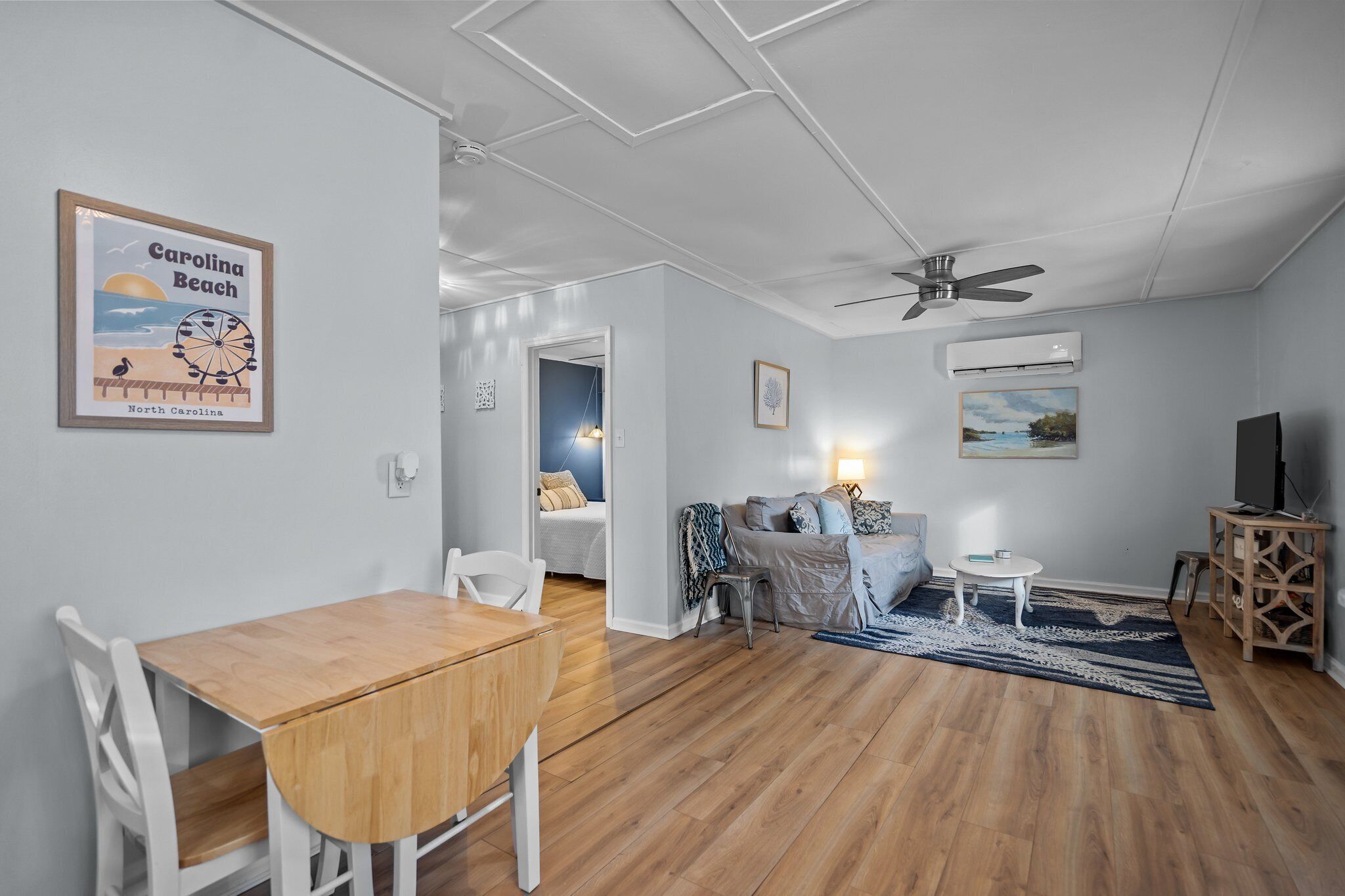 Een ruime woonkamer met een houten eettafel, een bank en een plafondventilator.