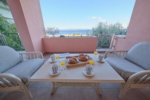 A balcony with a table set for breakfast, including croissants and orange juice, overlooking a scenic view. - Holiday Seaview Apartment by Litto (Split)