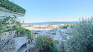Udsigt over kysten med en parkeringsplads, en bygning med grønt tag og en klar himmel.