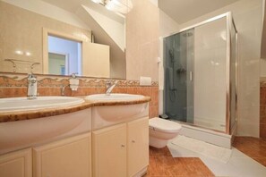 A bathroom with two sinks, a toilet, and a glass-enclosed shower. - Holiday Seaview Apartment by Litto (Split)