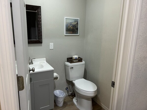 Un baño pequeño con inodoro, lavamanos y un cubo de basura.