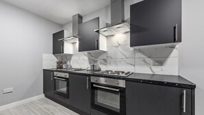 Una cocina moderna con armarios oscuros, salpicadero de mármol y electrodomésticos de acero inoxidable.