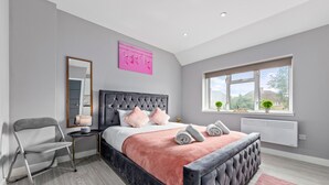Un dormitorio moderno con una cama grande, una mesita de noche, una silla y una ventana con vistas.