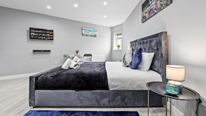 Ein modernes Schlafzimmer mit einem großen Bett, einem Nachttisch mit Lampe und Bildern an den Wänden.