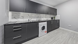 Eine moderne Küche mit dunklen Schränken, einer integrierten Waschmaschine und einer Marmor-Spritzschutzwand.