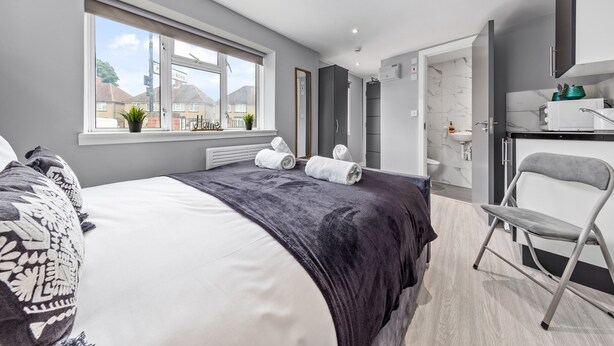 Une chambre d’hôtel moderne dotée d’un grand lit, offrant une vue sur l’extérieur, comprenant une salle de bain et un espace bureau.