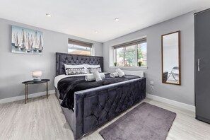 Une chambre moderne avec un grand lit, une table de chevet avec une lampe, une fenêtre donnant sur un beau paysage et un miroir au mur.