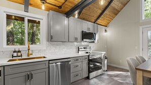 Una cucina moderna con mobili grigi, elettrodomestici in acciaio inossidabile e soffitto in legno.