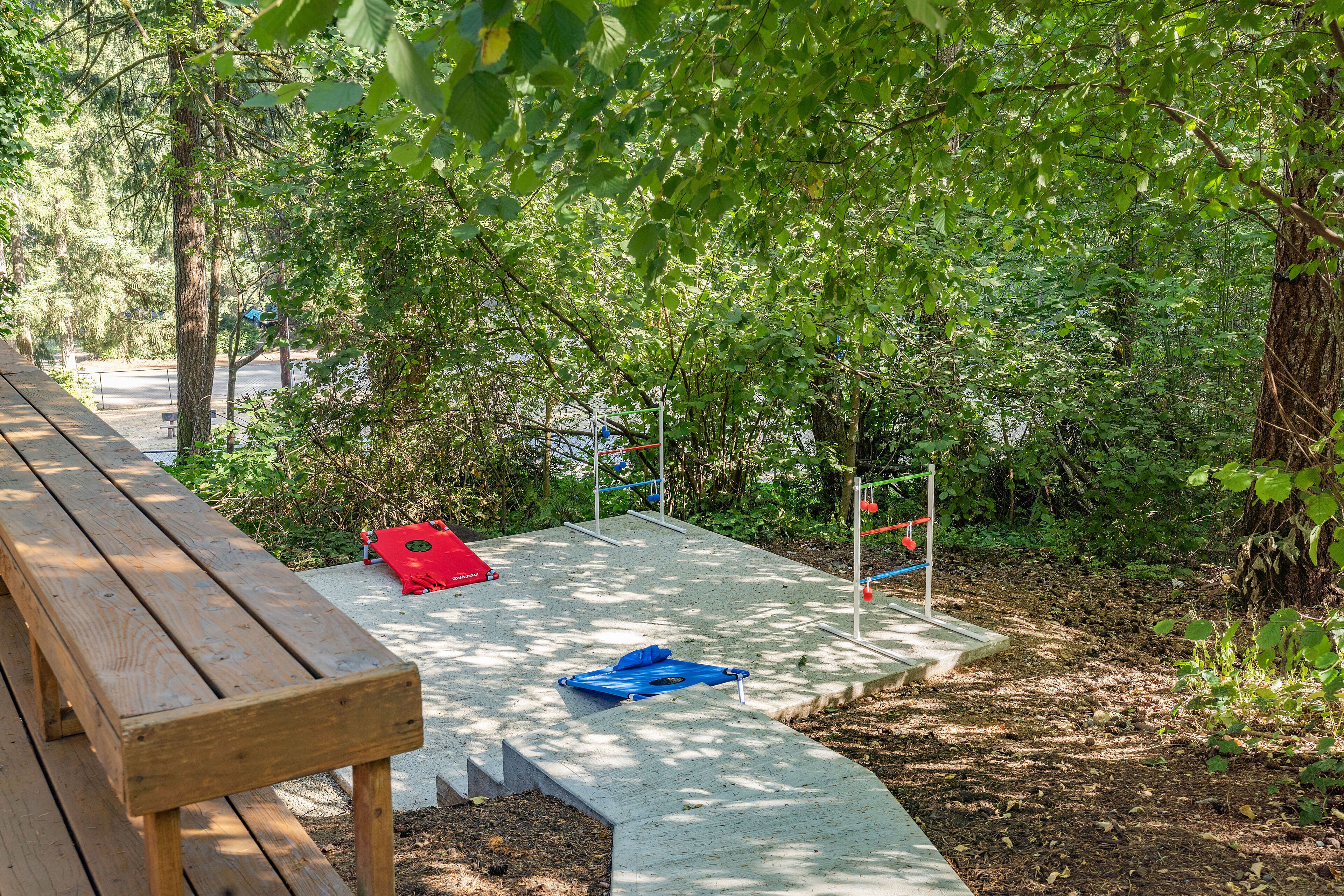 A wooden bench and a concrete pathway in a park with trees and a playground.
