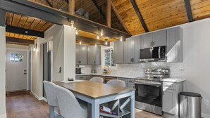 Una cucina moderna con mobili grigi, un tavolo da pranzo in legno e un forno a microonde in acciaio inossidabile.