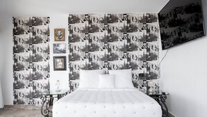 Un dormitorio con una cama, una mesita de cristal y una pared decorada con fotografías en blanco y negro.