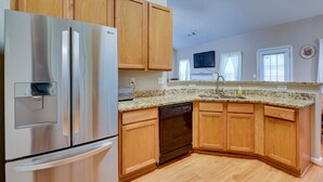 A kitchen with wooden cabinets, a stainless steel refrigerator, a dishwasher, and a granite countertop. - Inviting Austell Home: 14 Mi to Downtown Atlanta! (Austell)