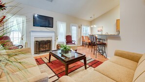 A living room with a fireplace, a television, and a dining area with chairs and a table. - Inviting Austell Home: 14 Mi to Downtown Atlanta! (Austell)