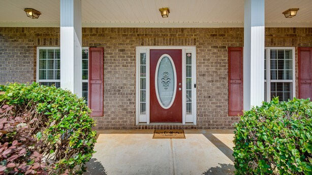 A brick building with a red door, white columns, and a welcome mat. - Inviting Austell Home: 14 Mi to Downtown Atlanta! (Austell)
