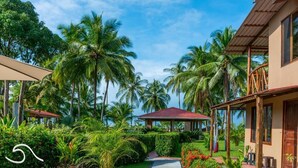Um resort tropical com palmeiras, uma galeria coberta e um gazebo.