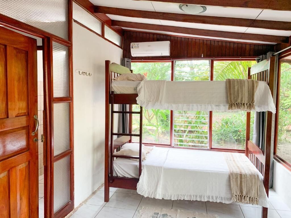 Una habitación con una cama individual, un escritorio pequeño y una ventana que da a zonas verdes.