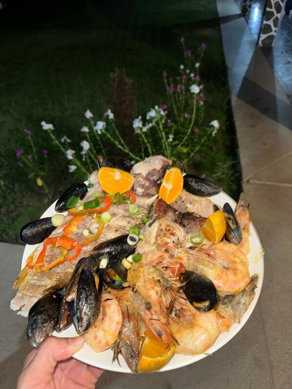 A plate of seafood including mussels, shrimp, and fish, garnished with lemon and green onions.