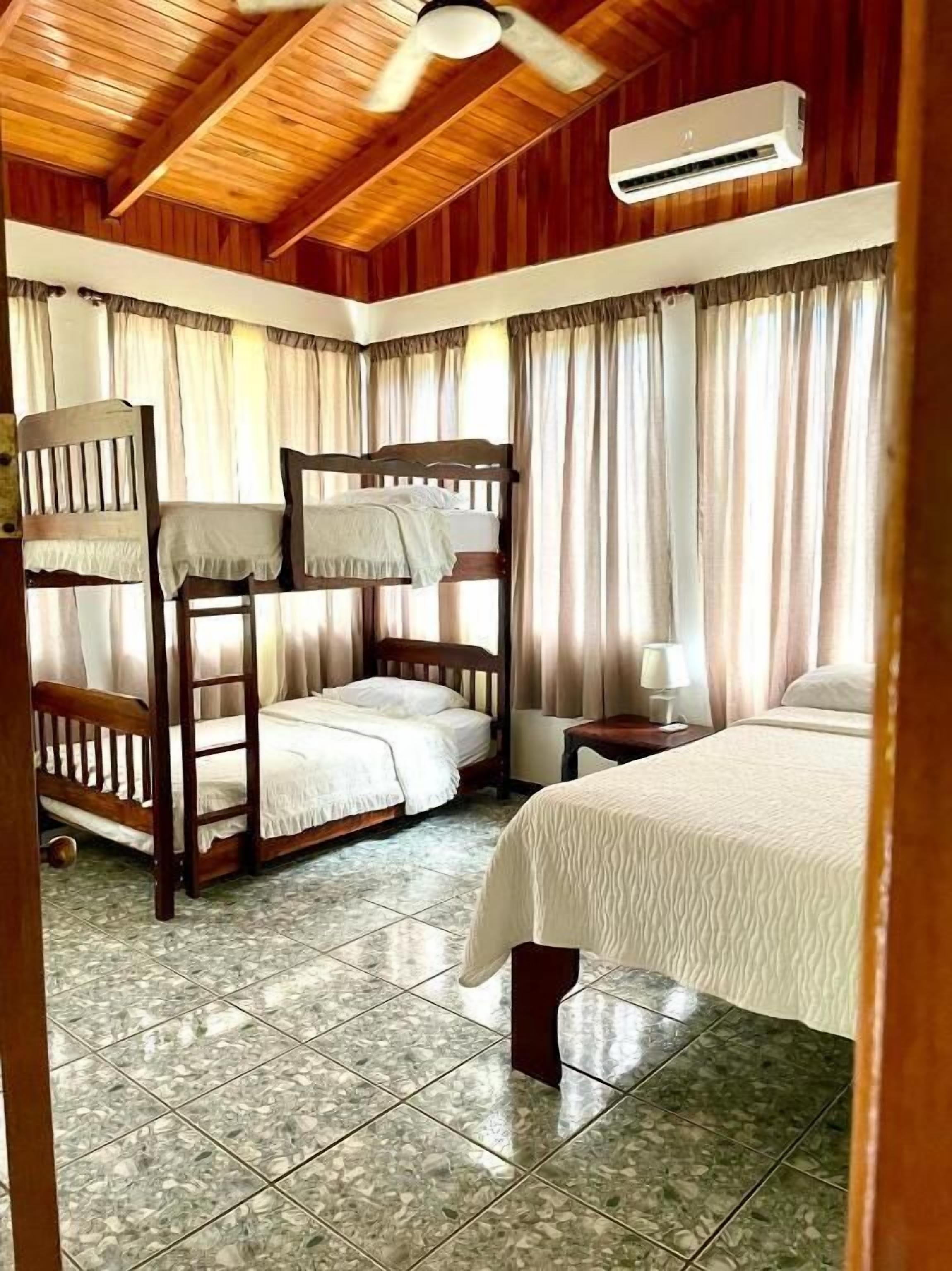 A bedroom with a bunk bed, a single bed, a nightstand, and a ceiling fan.