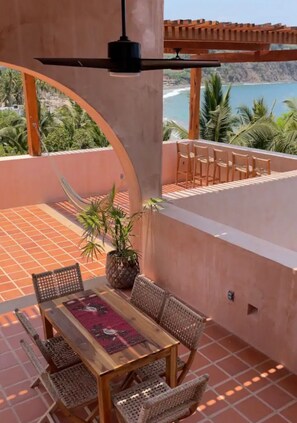 Relax on the terrace with a hammock, table, and chairs, taking in the serene coastal views of palm trees and the beach.