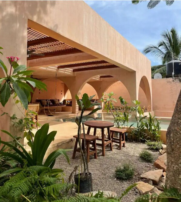 Relax in a serene outdoor space with a seating area, water feature, and lush greenery.