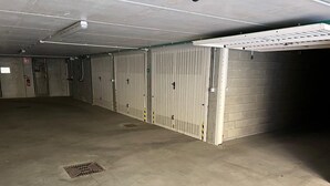 A large, empty parking garage with concrete floors and metal garage doors. - Lago Azzurro modern aparment with lake view and ba (Verbania)