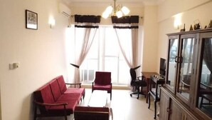 A living room with a sofa, armchairs, a coffee table, a TV cabinet, and a window with curtains. - Newly Renovated Spacious 2 Bedroom Apartment (Colombo)