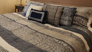 Une chambre à coucher avec un grand lit, une tête de lit, une table de chevet, une lampe et un tableau floral accroché au mur.