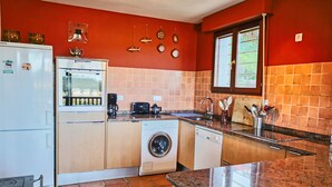 Een kleine keuken met een koelkast, wasmachine en koffiezetapparaat.