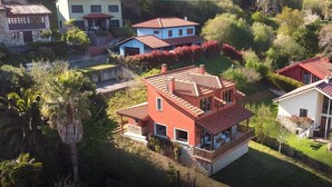 Een woonwijk met meerdere huizen, waaronder een herenhuis met balkon en een gelijkvloers huis met rood dak.