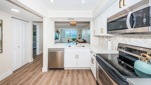 Une cuisine moderne avec des meubles blancs, des appareils électroménagers en acier inoxydable et un plancher en bois.