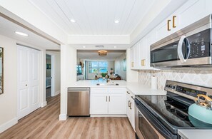 Een moderne keuken met witte kastjes, roestvrijstalen apparatuur en een houten vloer.