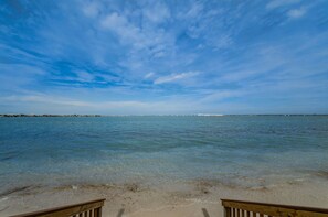 Een strand met helder water en een houten terras.