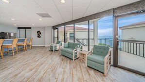 Un vaste espace intérieur doté d’un plancher en bois, de canapés verts et d’un coin repas avec des chaises.