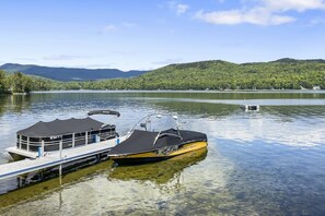 A boat docked at a pier with a clear view of a lake and mountains in the background.