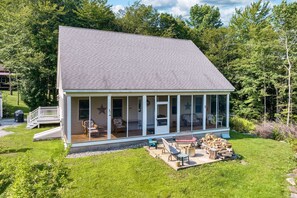 A single-story house with a large glass front, a covered porch, and a small deck.