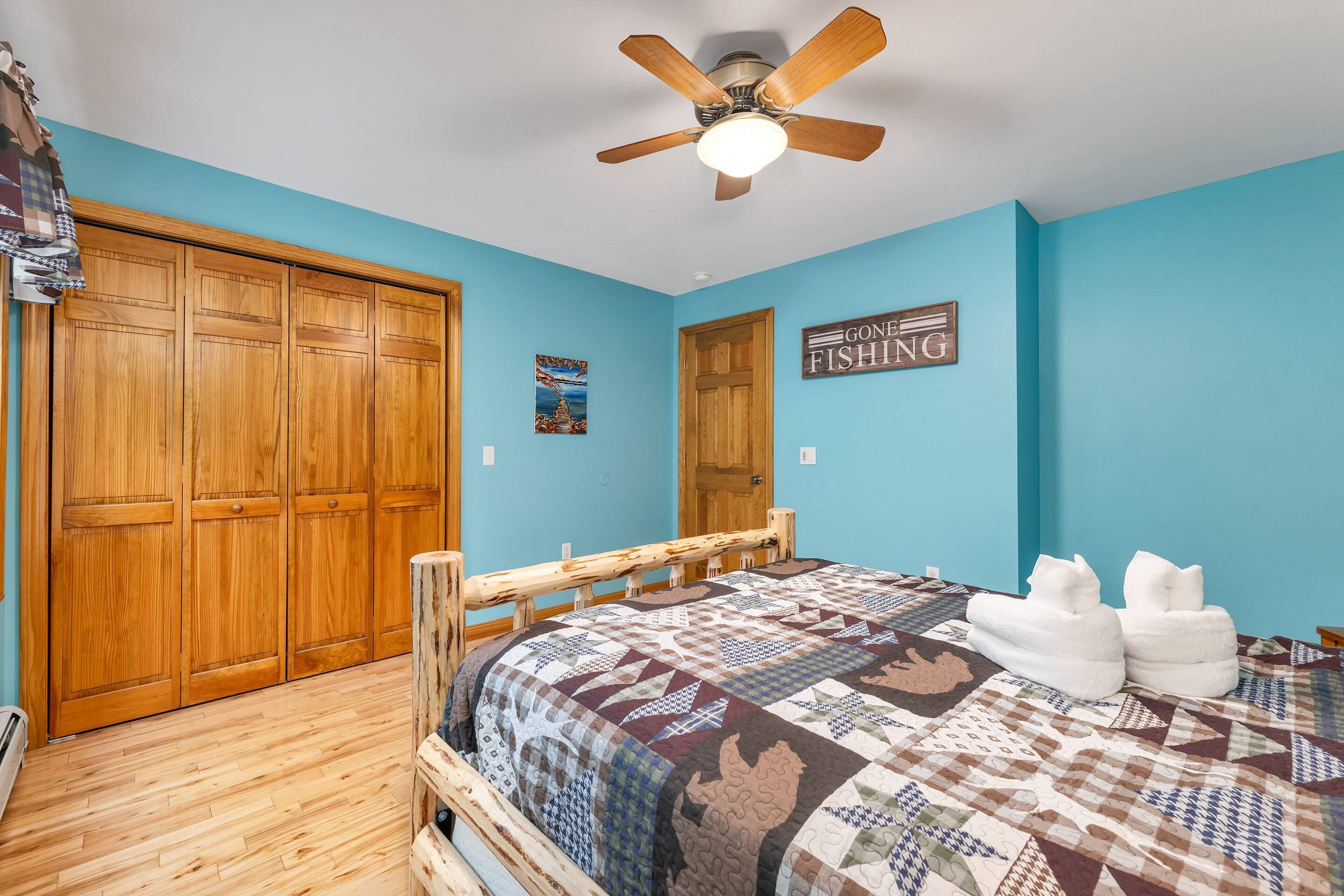 A bedroom with a wooden bed, a ceiling fan, and a blue wall.