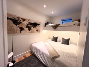 Un dormitorio con cama, un cuadro de un mapa, una ventana y un escritorio.