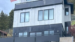 Une maison moderne à deux étages, dotée d’un garage, d’un mât portant le drapeau américain et d’un autre mât portant le drapeau suédois.
