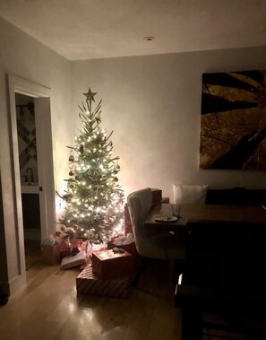 A room with a lit Christmas tree, a dining table, and a couch.