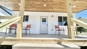 A wooden deck with two red chairs and a white door. - Cottage at Cave Run  (Salt Lick)