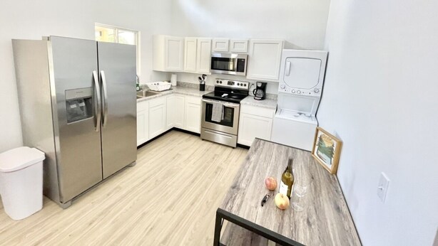 A modern kitchen with stainless steel appliances, white cabinetry, and a wooden dining table. - Cottage at Cave Run  (Salt Lick)
