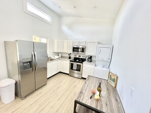 A modern kitchen with stainless steel appliances, white cabinetry, and a wooden dining table. - Cottage at Cave Run  (Salt Lick)
